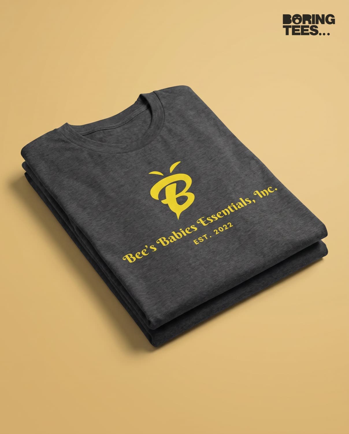 Folded charcoal heather tees with a yellow Bee's Babies Essentials bee logo printed centre chest