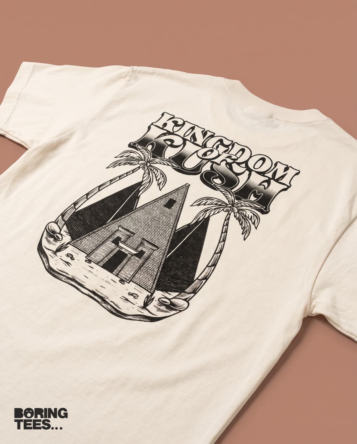 Cream tee with a black engraved-style illustration of Nubian pyramids and palm trees under Kingdom of Kush lettering