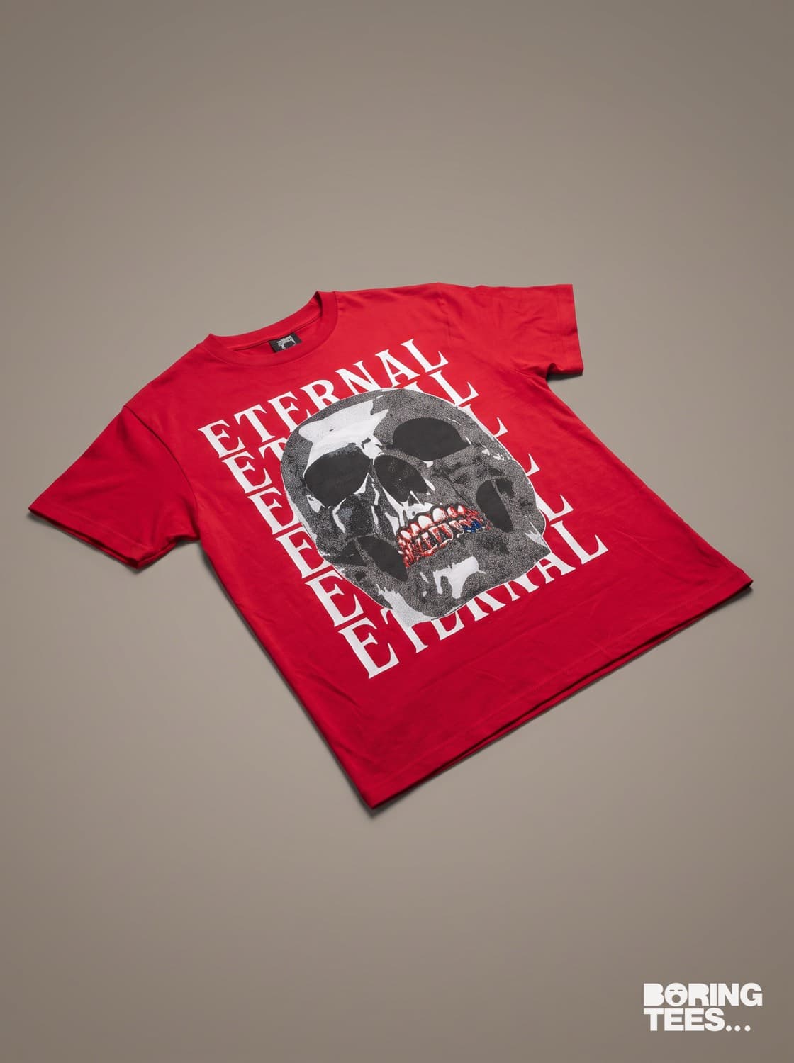 Red tee with an oversized halftone skull print over repeated white ETERNAL lettering