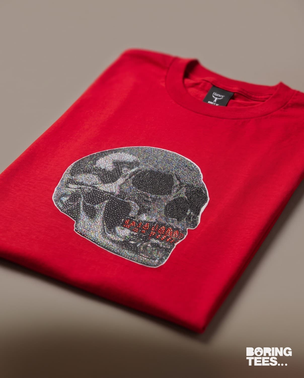 Folded red tee with a glitter-finish skull transfer on the chest