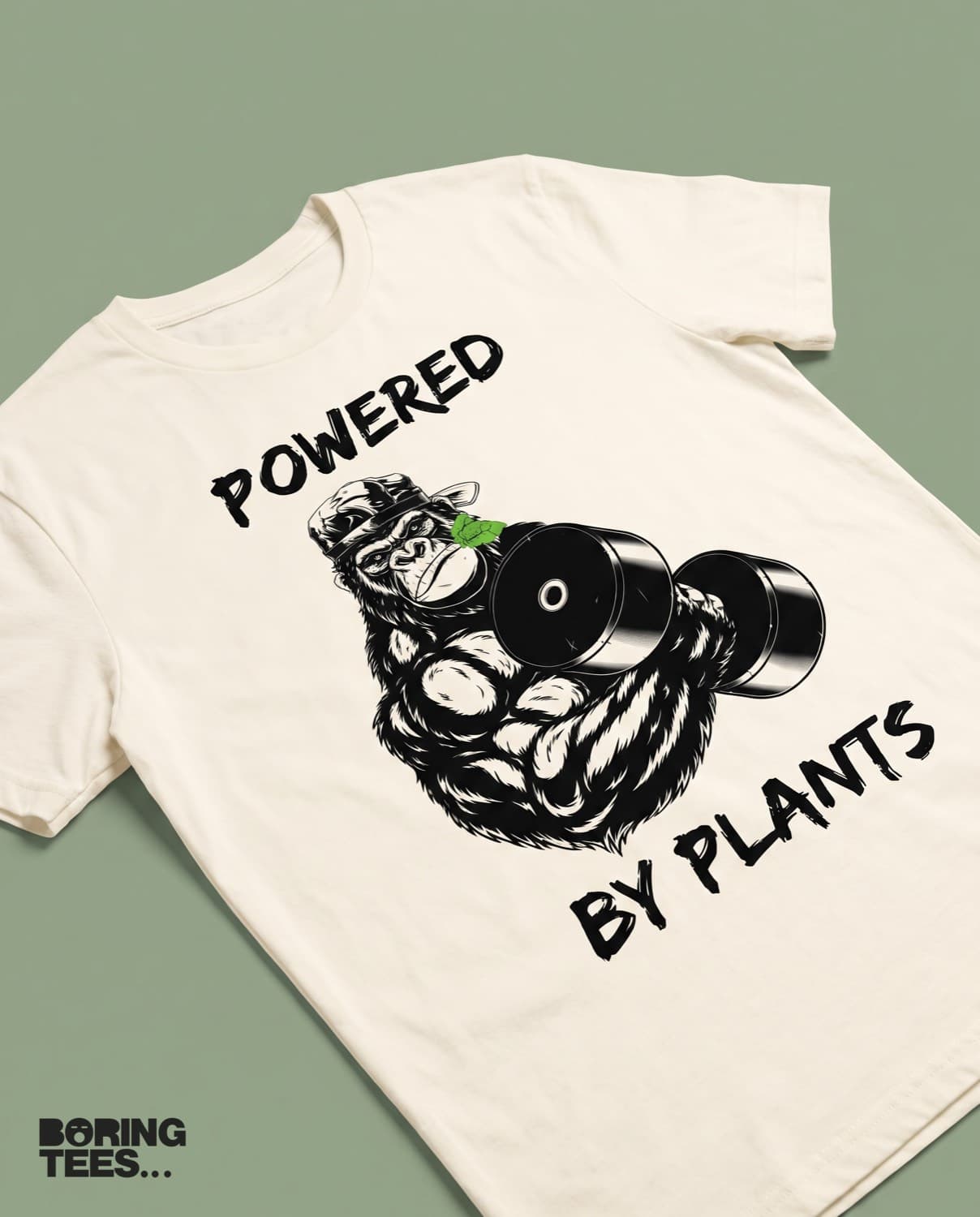 Cream tee with a black line-art gorilla lifting a dumbbell and the words POWERED BY PLANTS