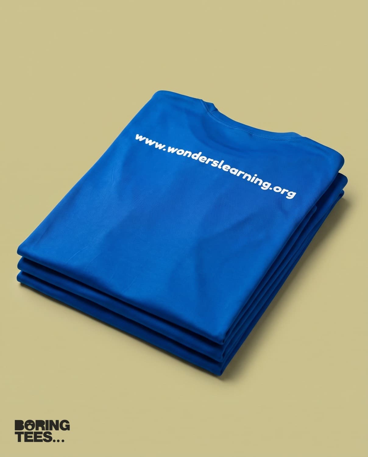 Folded stack of royal blue tees with the wonderslearning.org web address printed across the upper back